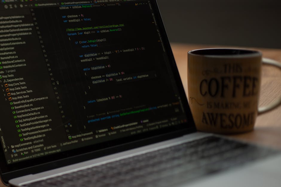 A close-up photograph of a computer screen displaying lines of code with syntax highlighting in multiple colours, including green, blue, pink, and white, on a dark background. The code appears to be w